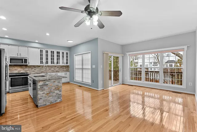 a large kitchen with kitchen island granite countertop a stove top oven a sink and wooden floors