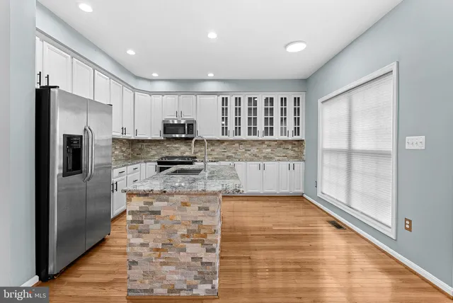 a large kitchen with granite countertop a refrigerator and a stove top oven