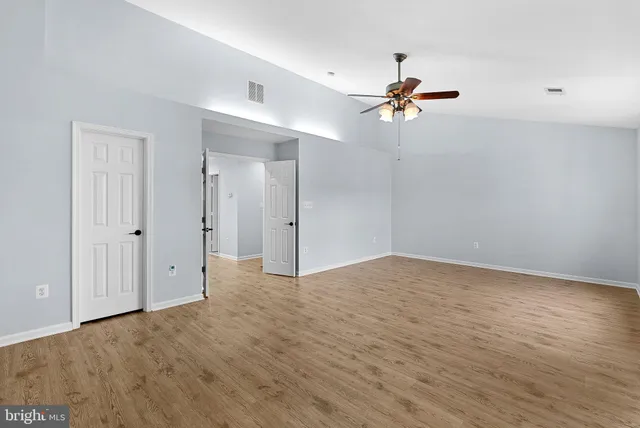 a view of an empty room with window and a chandelier fan