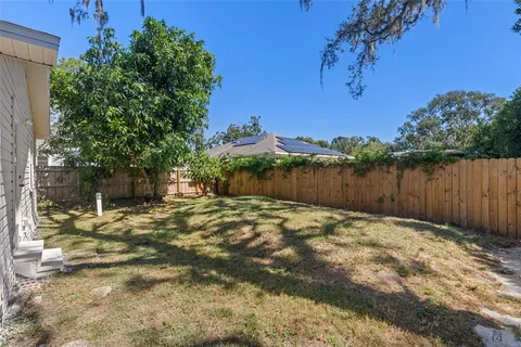 a view of a backyard with wooden fence and a large tree