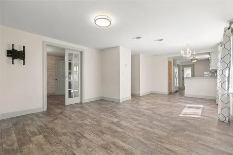 an empty room with kitchen view and wooden floor