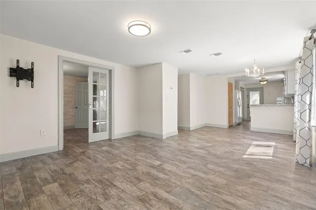 an empty room with kitchen view and wooden floor