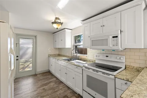 a kitchen with granite countertop a sink a stove and refrigerator