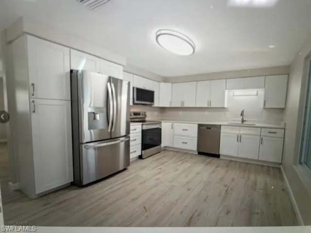 a kitchen with a refrigerator a sink and cabinets
