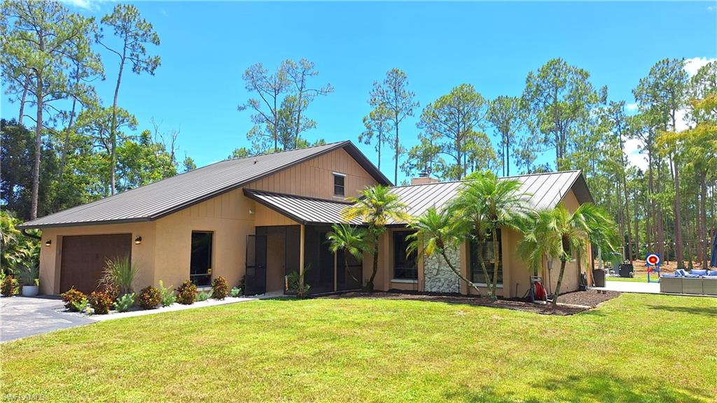3690 27th Avenue Southwest Naples, FL 34117 - Photo 2 of 32 View of front facade with a garage, a standing seam roof, a metal roof, and a front lawn