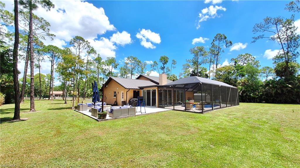 3690 27th Avenue Southwest Naples, FL 34117 - Photo 4 of 32 Back of house with a patio area, outdoor lounge area, a lanai, a yard, and a metal roof