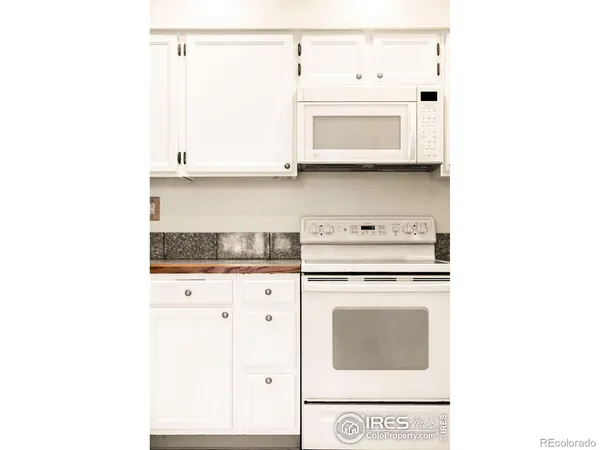 a kitchen with granite countertop white cabinets and white appliances