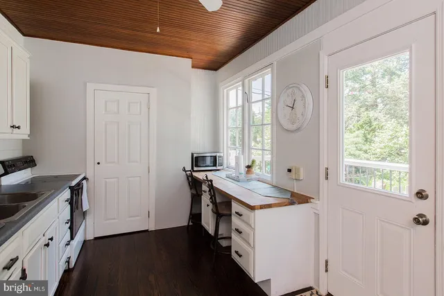 a kitchen with a stove a sink a window and wooden floor
