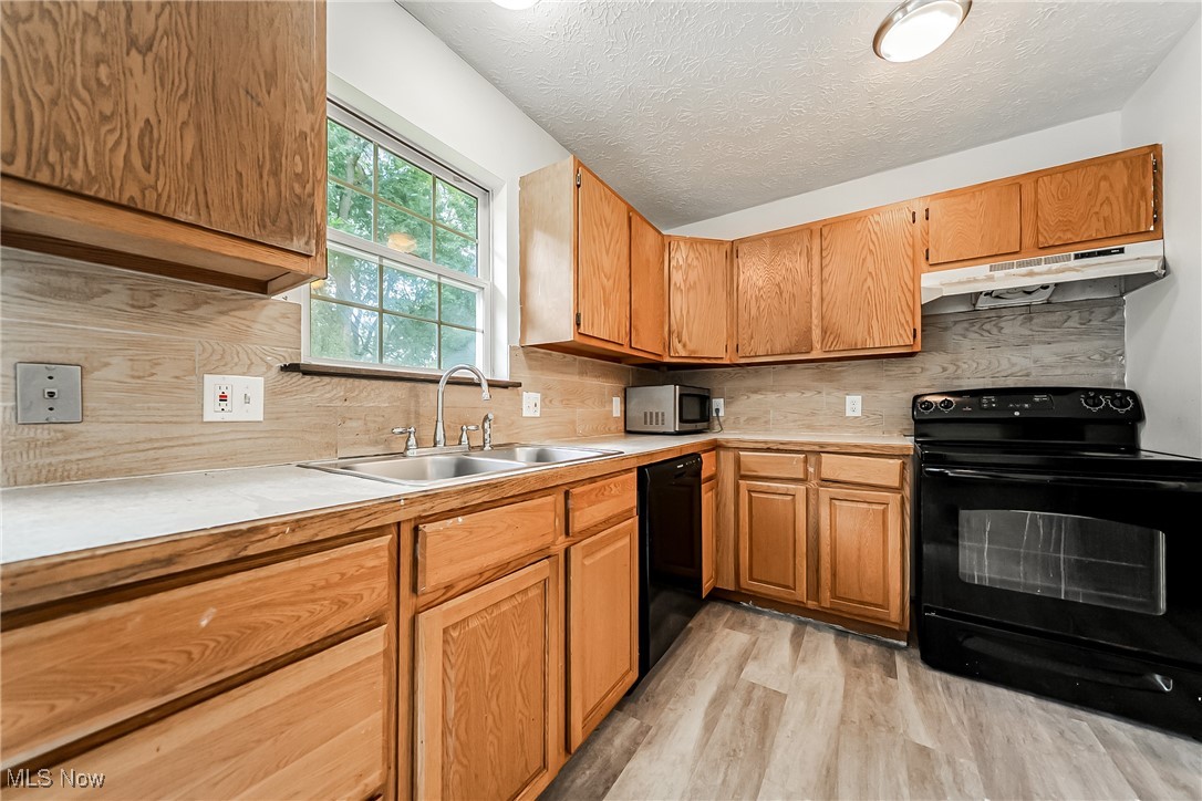 761 Garfield Street Akron, OH 44310 - Photo 12 of 31 Kitchen with black appliances, decorative backsplash, light countertops, a textured ceiling, and light wood-style floors