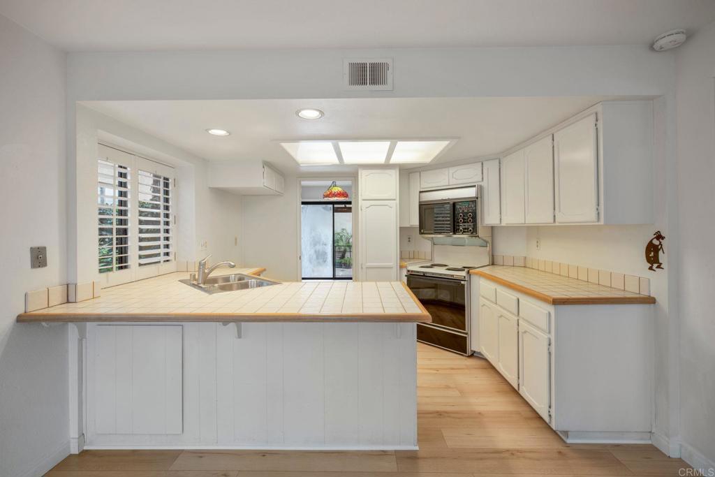 6882 Batiquitos Drive Carlsbad, CA 92011 - Photo 11 of 47 a kitchen with kitchen island granite countertop a stove top oven a sink dishwasher and white cabinets with wooden floor