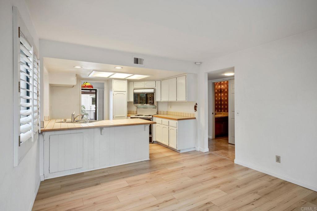 6882 Batiquitos Drive Carlsbad, CA 92011 - Photo 14 of 47 a large white kitchen with a sink and dishwasher a stove with wooden floor