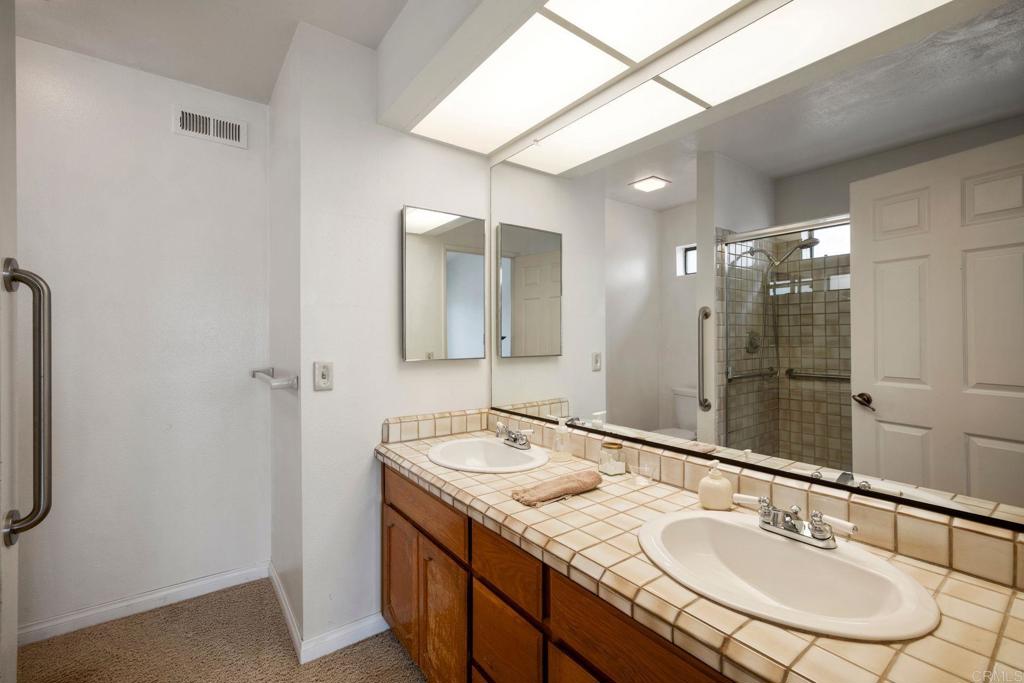 6882 Batiquitos Drive Carlsbad, CA 92011 - Photo 20 of 47 a bathroom with a granite countertop sink a mirror and a shower