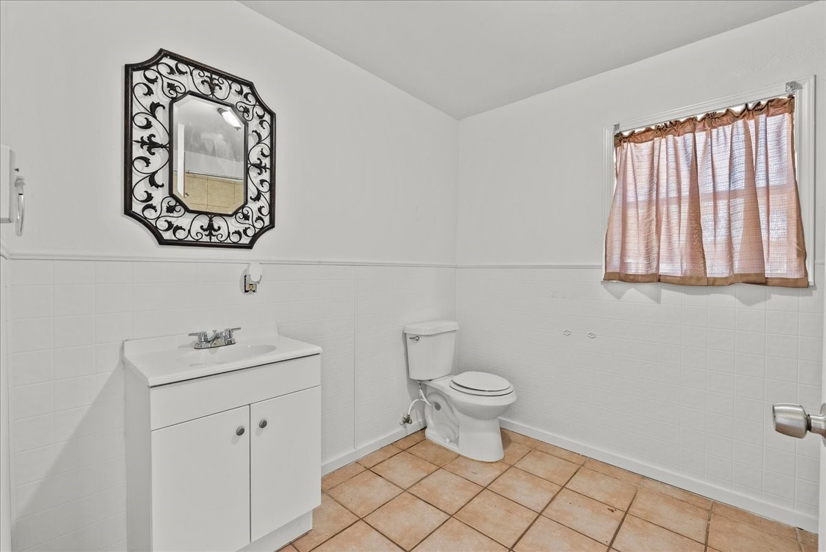1002 Orange Street La Marque, TX 77568 - Photo 22 of 31 a bathroom with a toilet a sink and a mirror
