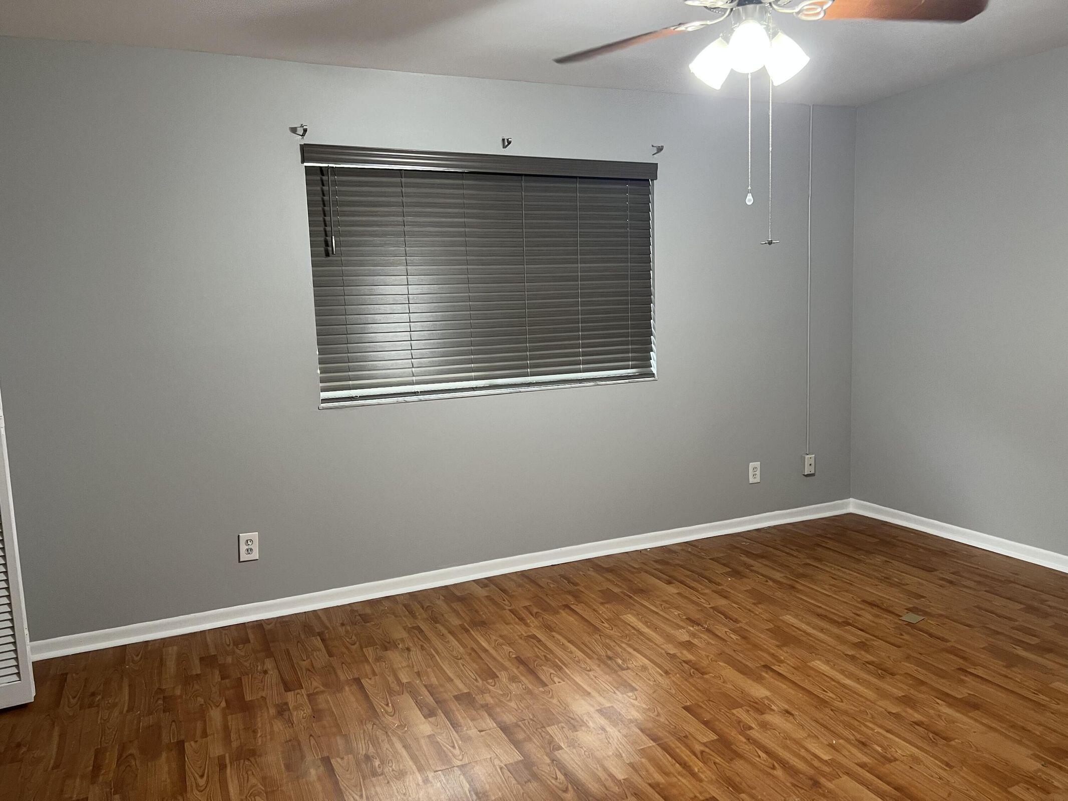 3405 Poolside Drive Greenacres, FL 33463 - Photo 24 of 32 an empty room with wooden floor and windows