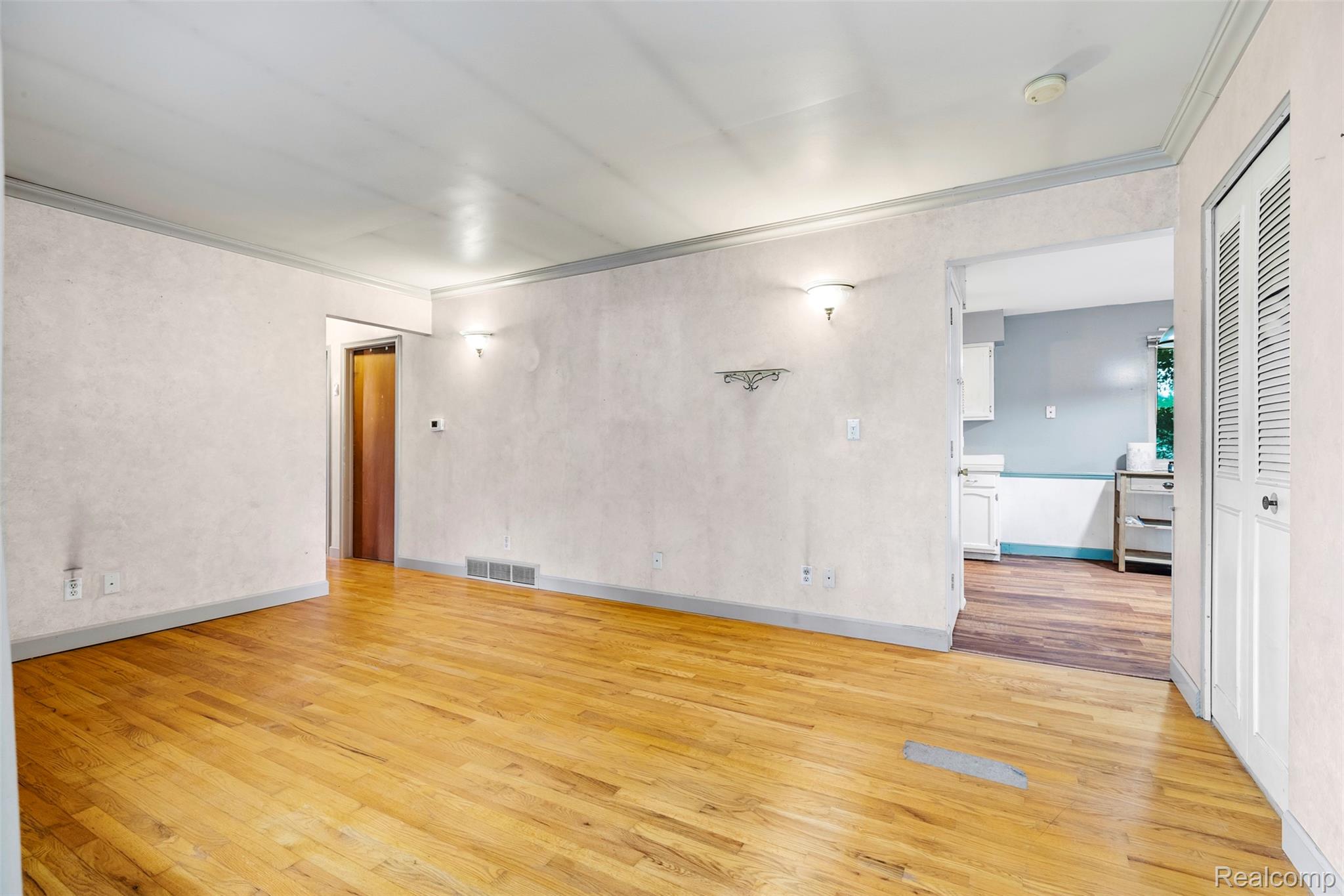 309 Windy Bluff Street Flushing, MI 48433 - Photo 6 of 32 Expansive interior space featuring wood-finish flooring, textured wall surfaces, decorative wall sconces, and crown molding