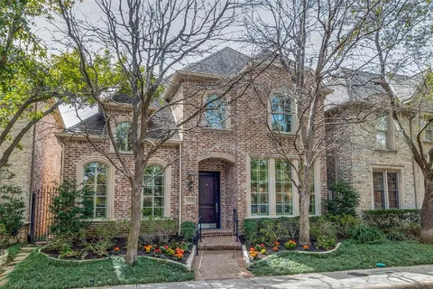 front view of a brick house with a yard and large trees