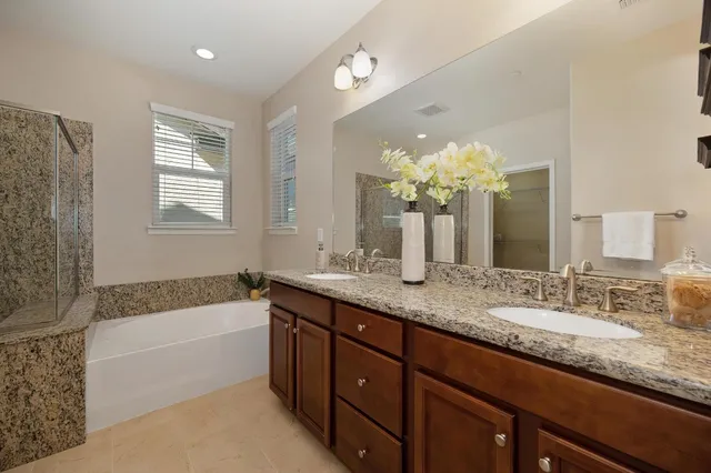 a bathroom with a granite countertop bathtub a double vanity sink and a bathtub