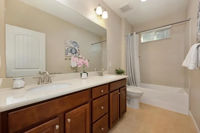 a bathroom with a double vanity sink toilet mirror and bathtub