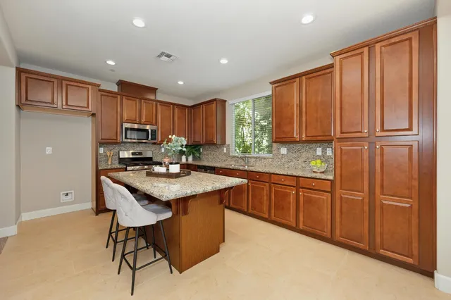 a kitchen with stainless steel appliances granite countertop wooden cabinets a center island and a refrigerator