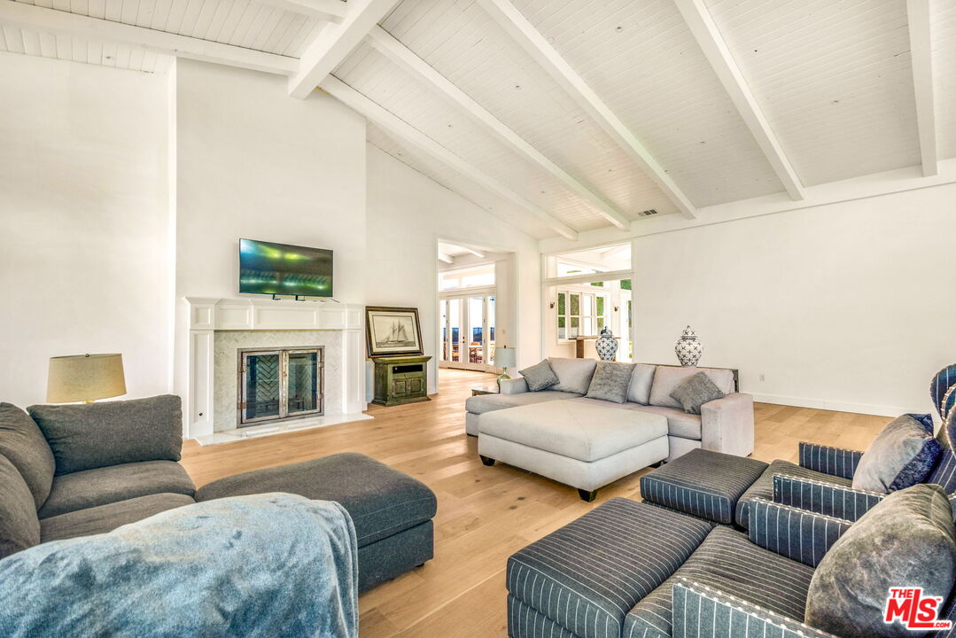9669 Oak Pass Road Beverly Hills, CA 90210 - Photo 16 of 37 a living room with furniture a fireplace and a flat screen tv
