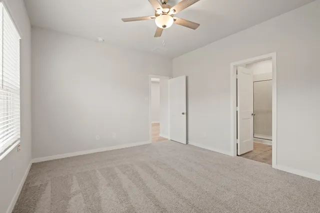 an empty room with a chandelier fan and windows
