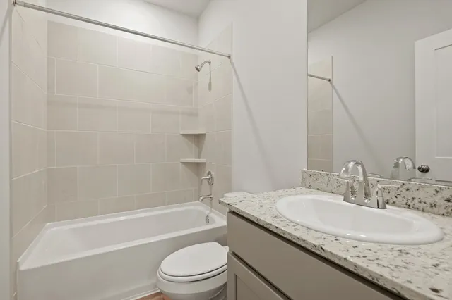 a bathroom with a granite countertop sink a toilet and shower