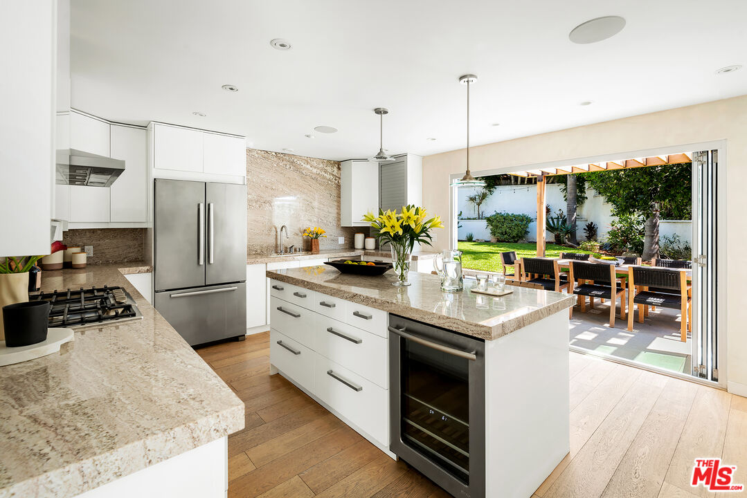1600 North Kings Road Los Angeles, CA 90069 - Photo 15 of 37 a kitchen with stainless steel appliances granite countertop a stove a refrigerator a oven a sink with a dining table and chairs