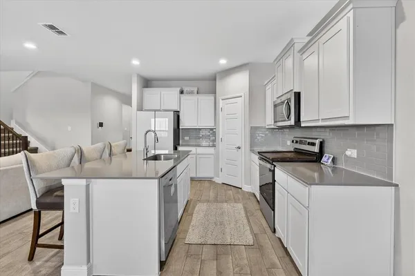 a kitchen with stainless steel appliances granite countertop a sink stove refrigerator and cabinets