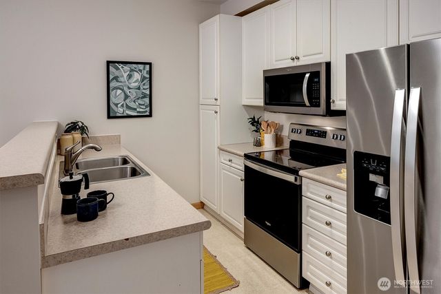 a kitchen with white cabinets and stainless steel appliances