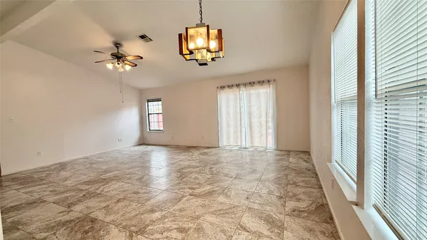 an empty room with windows and chandelier fan