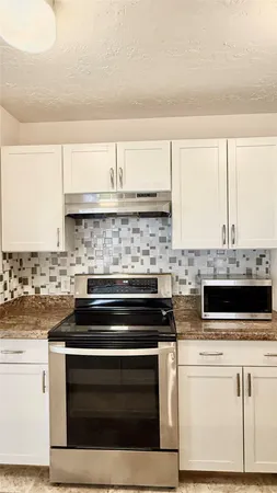 a kitchen with a refrigerator stove and white cabinets