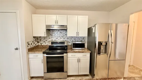 a kitchen with stainless steel appliances granite countertop a stove a microwave and a refrigerator