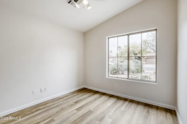 an empty room with wooden floor and windows