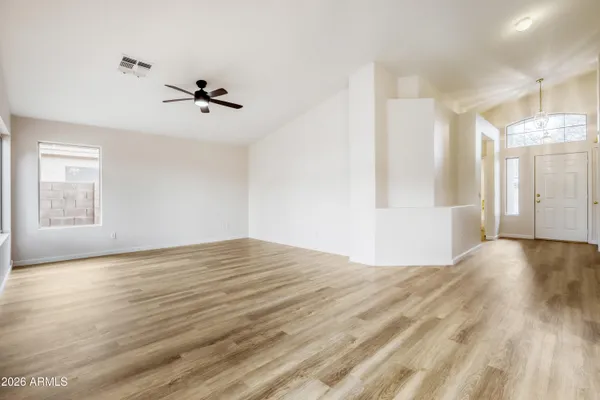 a view of empty room with wooden floor and fan