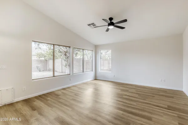 a view of empty room with wooden floor and fan