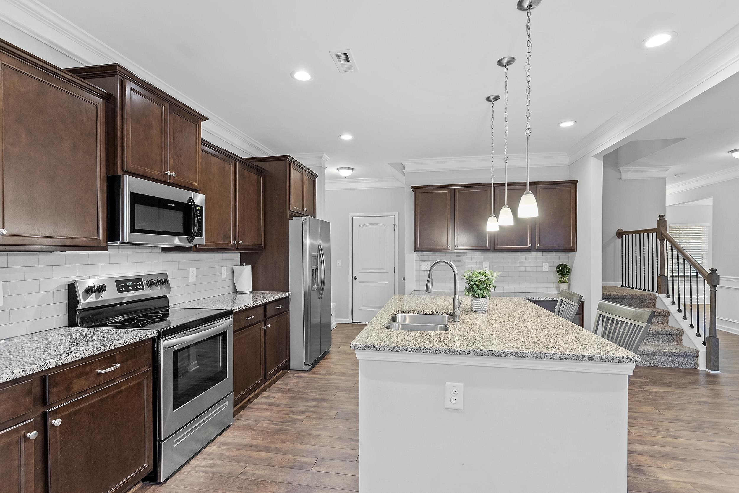 306 Springhill Lane Garner, NC 27529 - Photo 17 of 34 a kitchen with stainless steel appliances kitchen island granite countertop a sink a stove top oven a counter space and cabinets