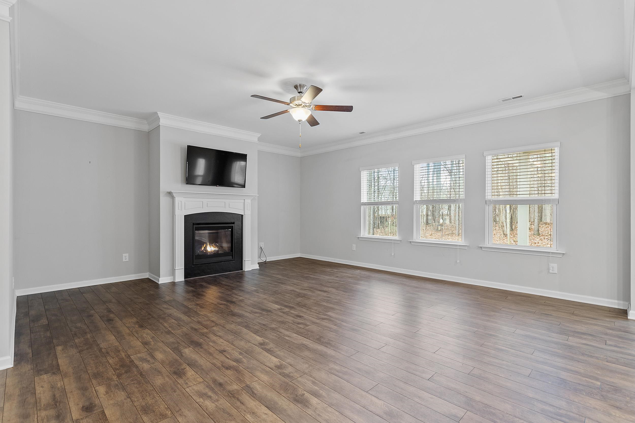 306 Springhill Lane Garner, NC 27529 - Photo 10 of 34 an empty room with windows fireplace and a kitchen view
