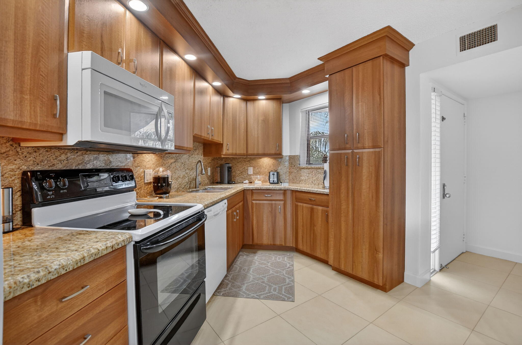 5851 Camino Del Sol, Unit 402 Boca Raton, FL 33433 - Photo 12 of 40 a kitchen with stainless steel appliances granite countertop a stove a sink and a refrigerator
