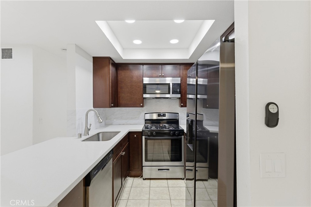 600 West 3rd Street, Unit A210 Santa Ana, CA 92701 - Photo 10 of 30 a kitchen with kitchen island a counter top space a stove and a refrigerator