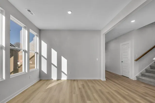 a view of an empty room with a window and wooden floor