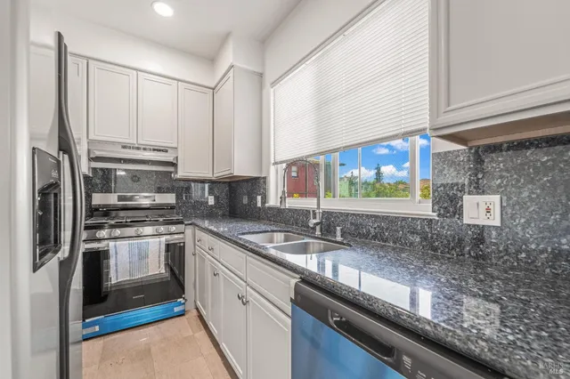 a kitchen with granite countertop a sink stainless steel appliances and cabinets