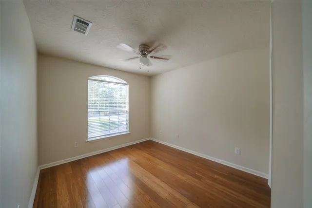 an empty room with wooden floor and windows