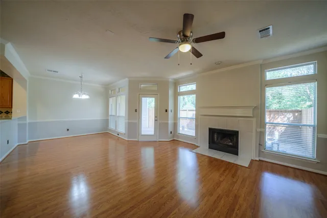 an empty room with wooden floor fireplace and windows