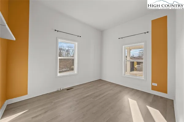 a view of an empty room with a window and wooden floor