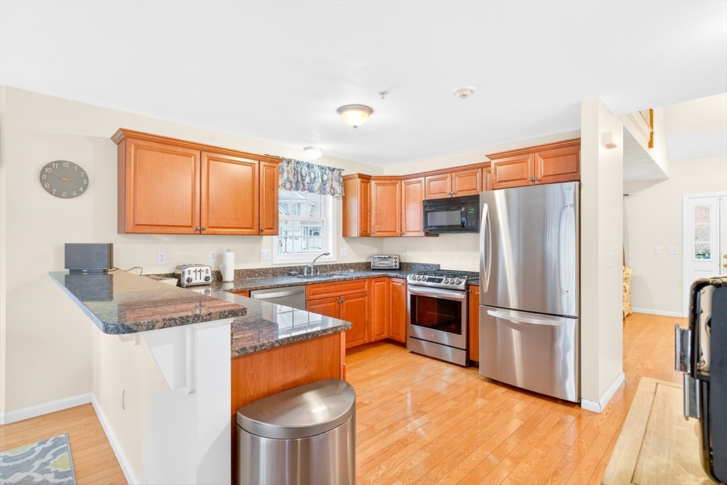 615 Nashua Road, Unit 9 Dracut, MA 01826 - Photo 11 of 38 a kitchen with stainless steel appliances granite countertop a refrigerator a stove a sink dishwasher and a refrigerator with wooden floor