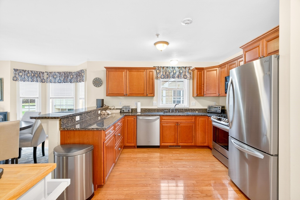 615 Nashua Road, Unit 9 Dracut, MA 01826 - Photo 9 of 38 a kitchen with stainless steel appliances granite countertop a refrigerator a stove a sink a dining table and chairs