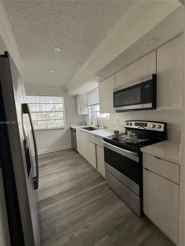 a large kitchen with stainless steel appliances granite countertop a stove a sink and a microwave