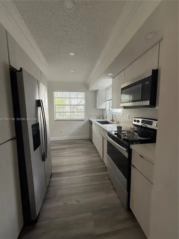 a large kitchen with stainless steel appliances granite countertop a stove a sink dishwasher a refrigerator and a stove top oven with wooden floor