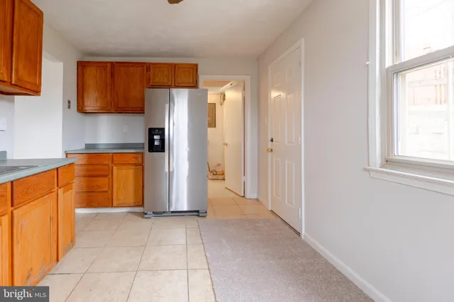 an empty room with a window and kitchen view
