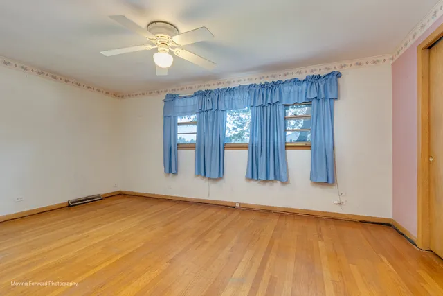a view of an empty room with window and wooden floor